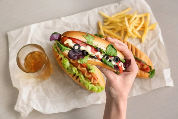 Frau isst leckeren Hot Dog am Tisch — Stockfoto