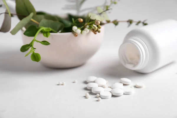 Garrafa com pílulas e ervas no fundo claro — Fotografia de Stock