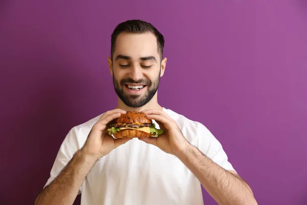 背景色でおいしいハンバーガーを食べる人 — ストック写真