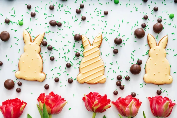 Easter cookies with chocolate candies and tulips on white background — Stock Photo, Image
