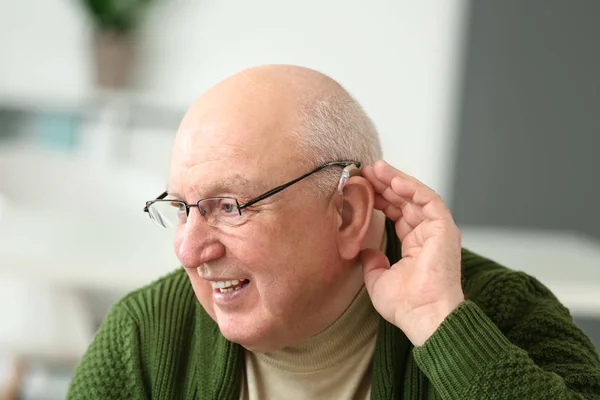 Uomo anziano con apparecchio acustico a casa — Foto Stock