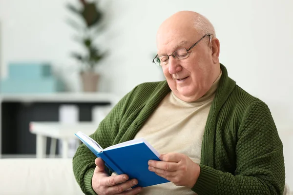 Senior man met gehoorapparaat lezen boek thuis — Stockfoto