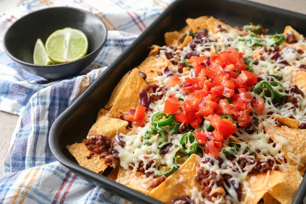 Prato de cozimento com nachos saborosos, carne picada, queijo e salsa na mesa — Fotografia de Stock