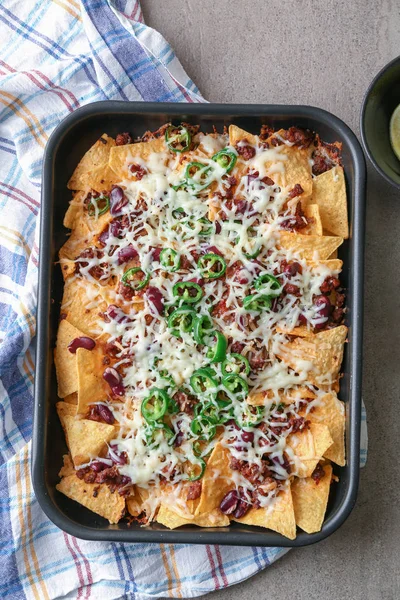 Prato de panificação com nachos saborosos, carne picada, queijo e pimenta na mesa cinza — Fotografia de Stock