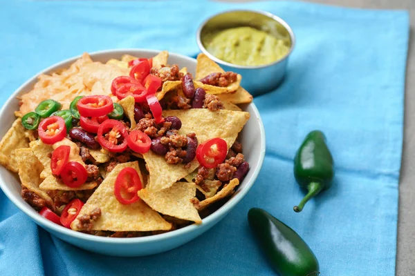 Prato com nachos saborosos, carne picada e pimenta na mesa — Fotografia de Stock