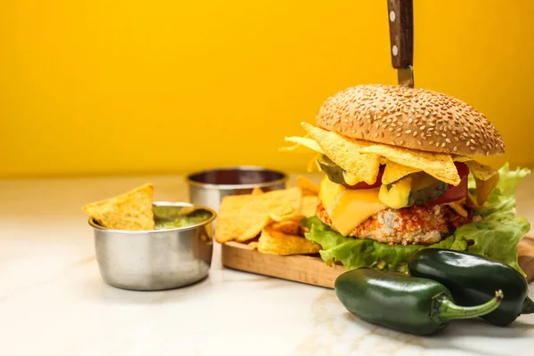 Hambúrguer saboroso com nachos e guacamole na mesa — Fotografia de Stock