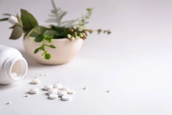 Garrafa com pílulas e ervas no fundo claro — Fotografia de Stock