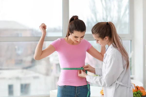 Дієтолог вимірює талію молодої жінки в клініці втрати ваги — стокове фото