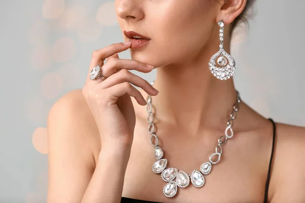 Ung kvinna med vackra smycken på ljus bakgrund, närbild — Stockfoto