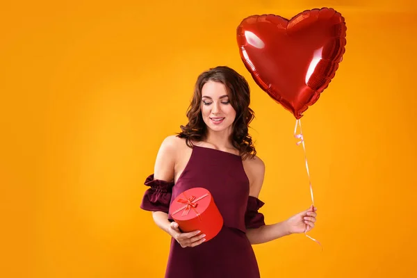 美丽的年轻妇女与礼物和心形气球在颜色背景 — 图库照片