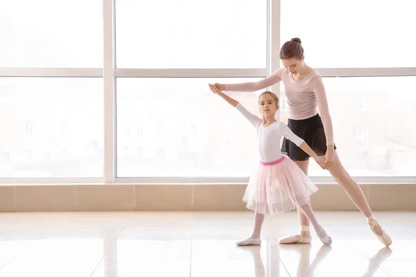 Little ballerina training with coach in dance studio