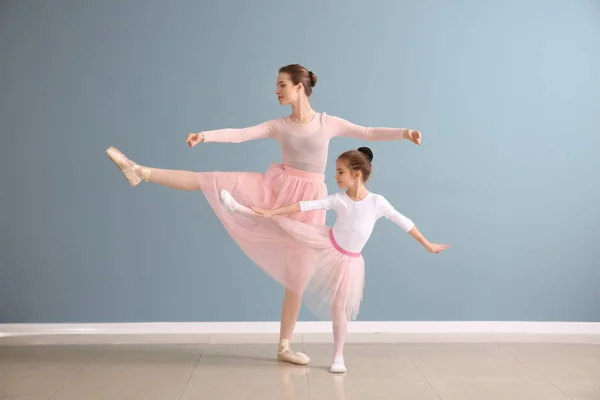 Pequeña bailarina con entrenador contra la pared de color — Foto de Stock