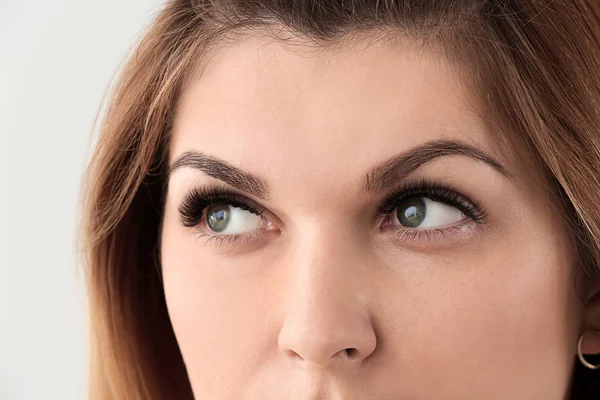 Young woman with beautiful eyelashes on light background, closeup — Stock Photo, Image