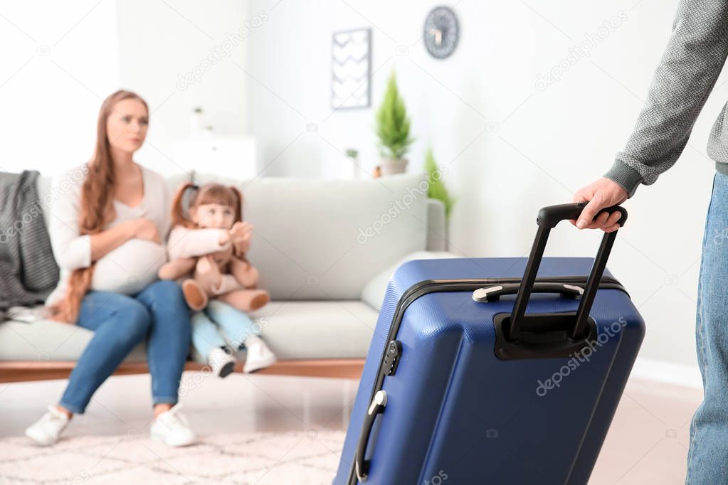 Man with suitcase leaving his family