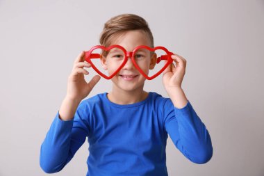 Işık arka planda büyük kalp şeklinde gözlük ile komik küçük çocuk