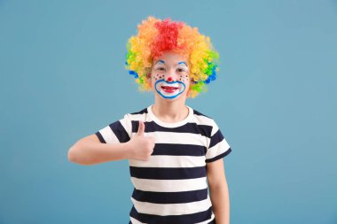 Palyaço makyaj gösteren başparmak-up renk arka plan üzerinde şirin küçük çocuk. April fools'day kutlama