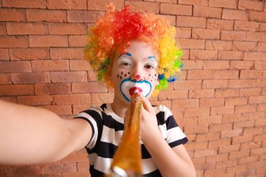 Palyaço makyajlı şirin bir çocuk duvara selfie çekiyor. 1 Nisan kutlamaları
