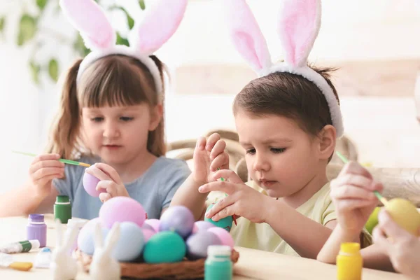 Enfants mignons peignant des œufs de Pâques à la maison — Photo