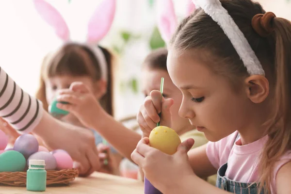 Milé děti maluje velikonoční vejce doma — Stock fotografie