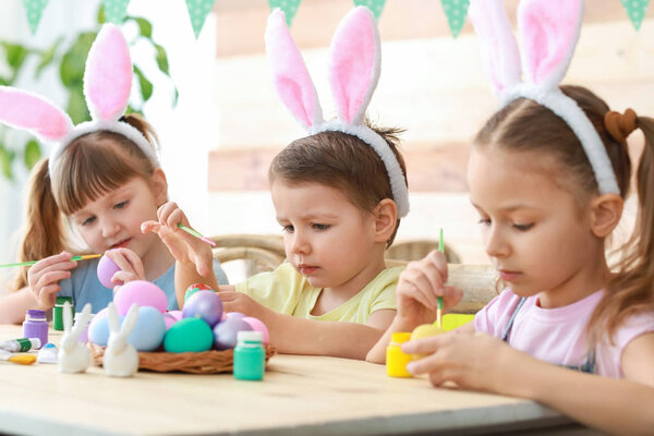Милые дети рисуют пасхальные яйца дома
