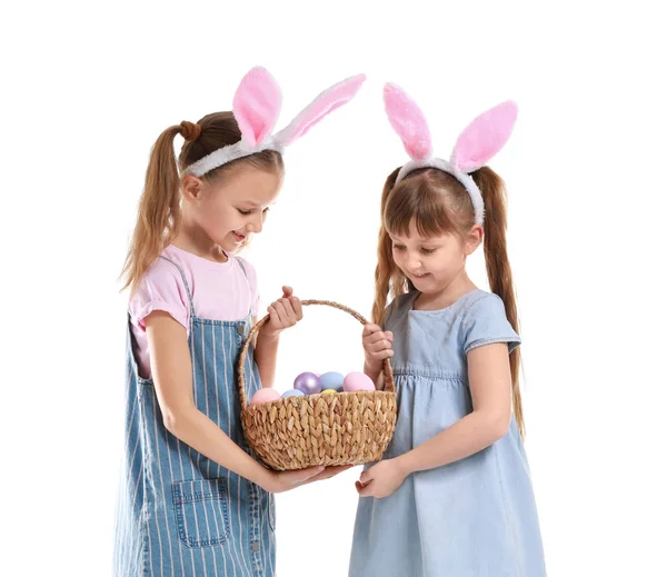 Niedlichen kleinen Mädchen mit Korb von Ostereiern und Hasenohren auf weißem Hintergrund — Stockfoto