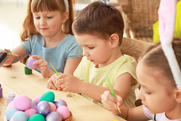 Милые дети рисуют пасхальные яйца дома — стоковое фото