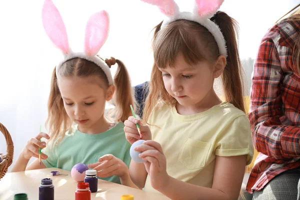 Cute little children painting Easter eggs at home