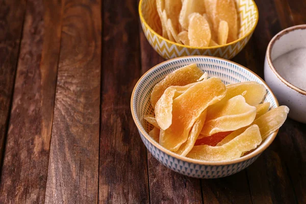 Bowl with tasty dried mango on wooden background