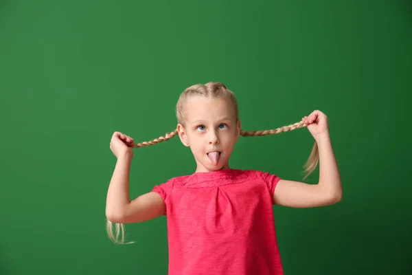 Malá ušklípací dívka na barevném pozadí — Stock fotografie
