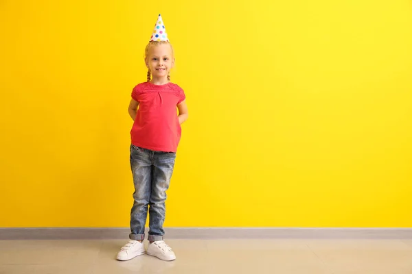 Funny little girl in party hat on color background — Stock Photo, Image