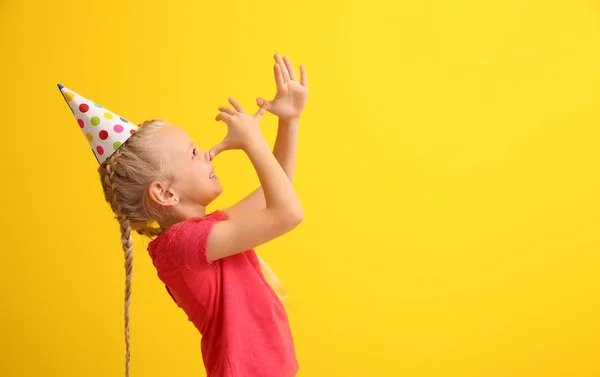 Legrační malá holčička v party hat šklebící se na barvu pozadí. Apríla oslava — Stock fotografie