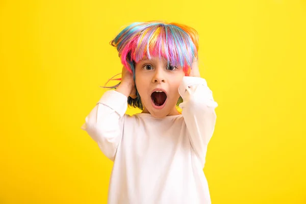 Shocked little girl in bright wig on color background — Stock Photo, Image