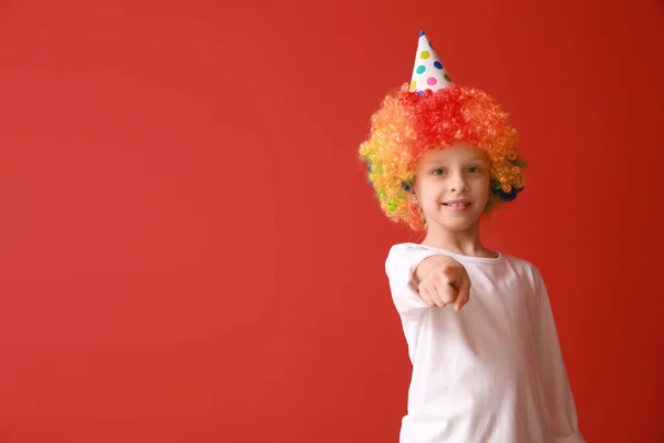 Funny klein meisje in heldere pruik wijzend op kijker op kleur achtergrond. April Fools ' dag viering — Stockfoto