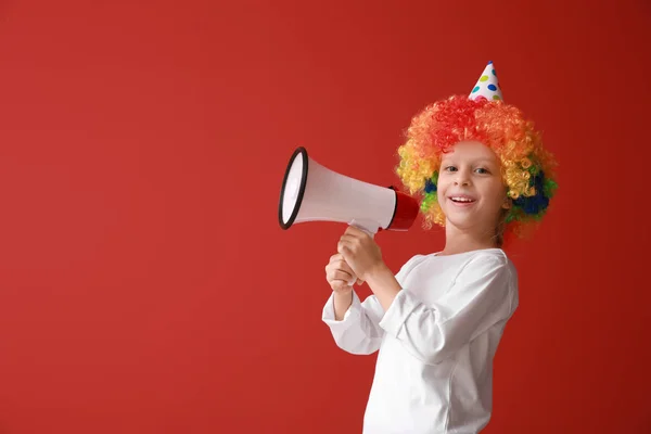 Niña divertida en peluca brillante y con megáfono sobre fondo de color. Celebración del Día de los Inocentes — Foto de Stock