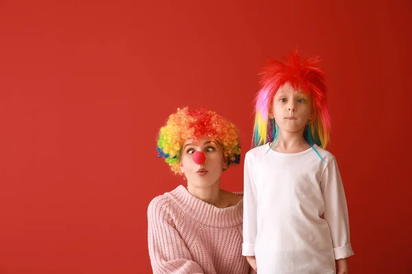 Woman and little girl in funny disguise on color background. April fools' day celebration — Stock Photo, Image