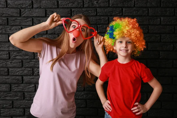 Mujer y niña en disfraz divertido sobre fondo oscuro. Celebración del Día de los Inocentes — Foto de Stock