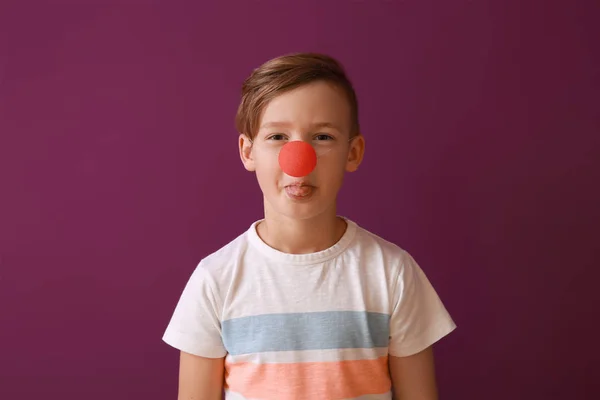 Забавный маленький мальчик с клоунским носом на цветном фоне. Празднование Дня дураков — стоковое фото