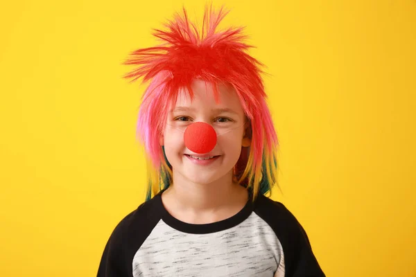Funny little boy with clown nose and wig on color background. April fools' day celebration — Stock Photo, Image