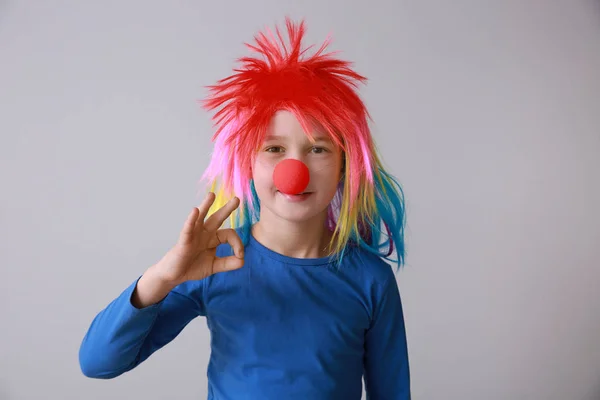 Ragazzino divertente con naso da clown e parrucca che mostra OK su sfondo chiaro. Festa degli sciocchi di aprile — Foto Stock