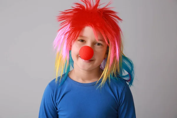 Funny little boy with clown nose and wig on light background. April fools' day celebration — Stock Photo, Image