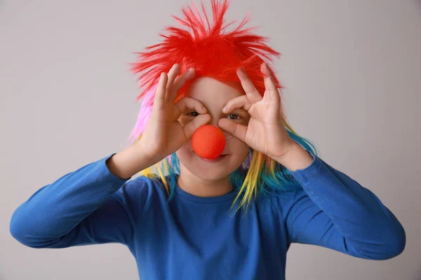 Funny little boy with clown nose and wig on light background. April fools' day celebration — Stock Photo, Image