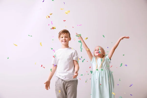 Schattige kleine kinderen en dalende confetti op lichte achtergrond — Stockfoto