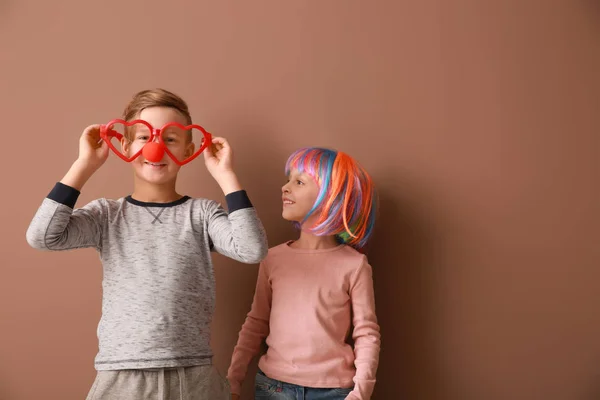 Little children in funny disguise on color background. April fools' day celebration — Stock Photo, Image