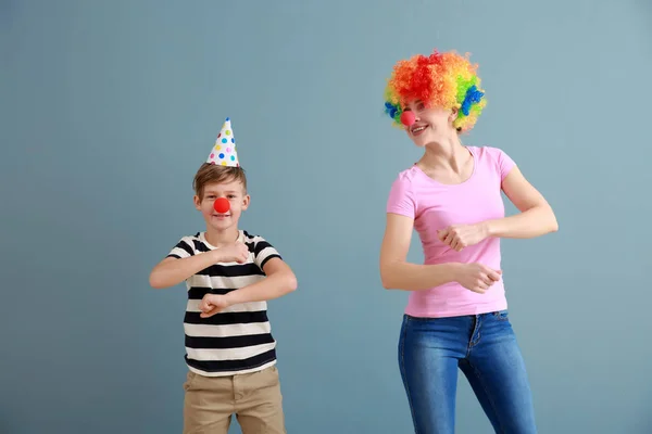 Niño y su madre disfrazados de divertido en el fondo de color. Celebración del Día de los Inocentes — Foto de Stock