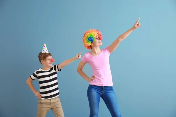 Little boy and his mother in funny disguise on color background. April fools' day celebration — Stock Photo, Image