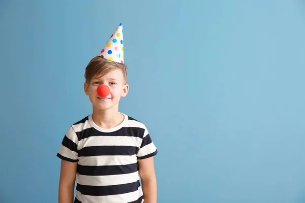 Маленький хлопчик з клоуном і вечірнім капелюхом на кольоровому фоні. квітня святкування дня дурнів — стокове фото