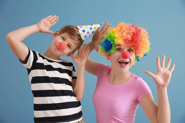 Niño y su madre disfrazados de divertido en el fondo de color. Celebración del Día de los Inocentes — Foto de Stock