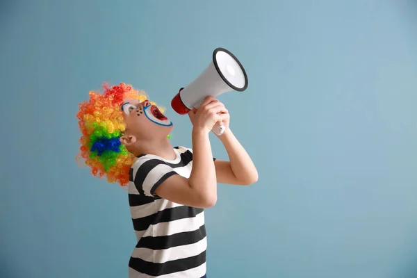 Petit garçon mignon avec maquillage de clown et mégaphone sur fond de couleur. Fête des fous d'avril — Photo