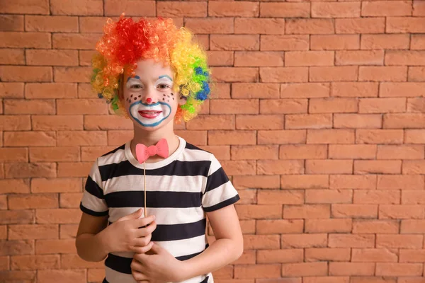 Ένα χαριτωμένο αγοράκι με μακιγιάζ κλόουν στον τοίχο. Πρωταπριλιά ημέρα εορτασμού — Φωτογραφία Αρχείου