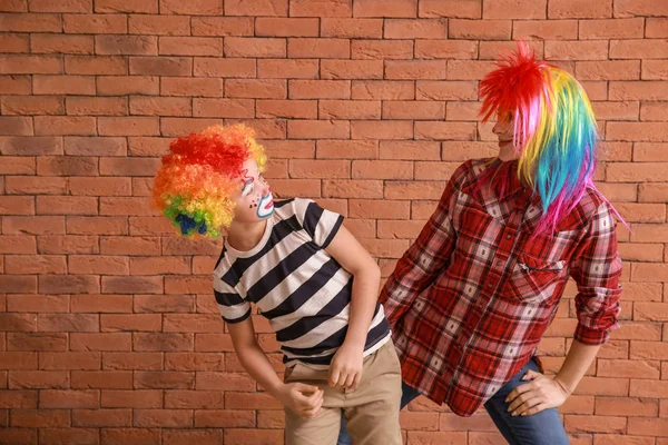 Woman and her little son in funny disguise against brick wall. April fools' day celebration — Stock Photo, Image